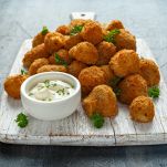 Homemade Breaded Garlic Mushrooms with sour cream and parsley on white wooden board