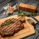 Pork steak on wooden Board with herbs, garlic and black pepper