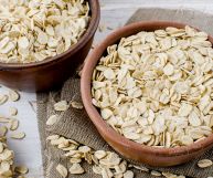 Due scodelle marroni contenenti fiocchi d’avena, sparsi anche sulla iuta e sul tavolo sottostante; possono essere usati per colazione, barrette e dolci