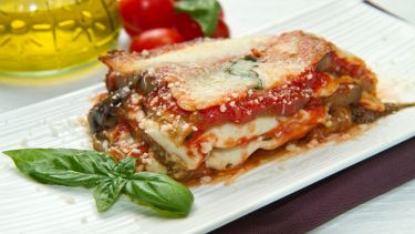 Parmigiana di melanzane impiattata con basilico fresco