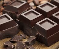 Cioccolato fondente marrone scuro riprodotto in una composizione che presenta blocchi, quadretti dalle grandi dimensioni e scaglie