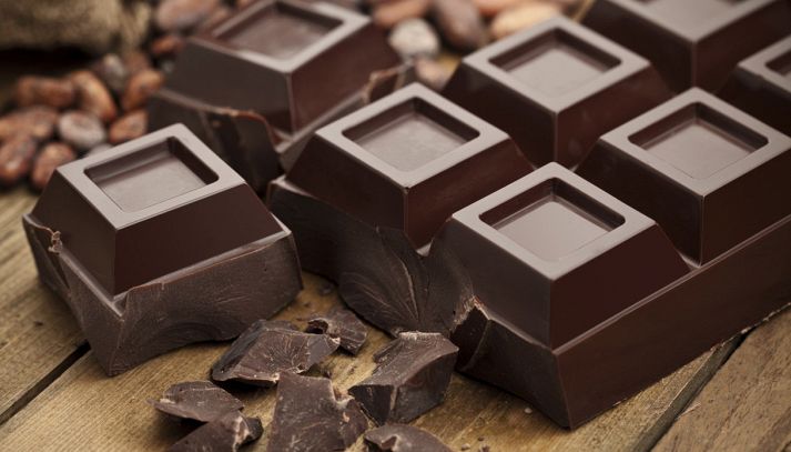Cioccolato fondente marrone scuro riprodotto in una composizione che presenta blocchi, quadretti dalle grandi dimensioni e scaglie