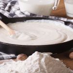 preparation of bechamel sauce in a pan and flour, milk on the table. horizontal