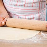 Mani di donna stendono l'impasto della focaccia