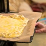 Donna mette nel forno la teglia con la focaccia
