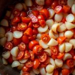 Pomodori pelati aggiunti alle cipolle in casseruola.