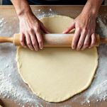 Sfoglia stesa sul piano con mattarello.