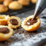 Tagliate a metà i bignè raffreddati e riempiteli con la crema al cioccolato