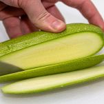Donna taglia la zucchina a fette lunghe e sottili