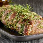 Strofinate il carrè di maiale con gli spicchi d'aglio per far insaporire la carne. Trasferitelo in una terrina e cospargetelo con timo, maggiorana, prezzemolo tritato, alloro e cipolla affettata. Aggiungete pepe e olio extravergine d'oliva. Coprite con pellicola trasparente e lasciate marinare in frigorifero per almeno 12 ore.