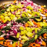 Preriscaldate il forno a 200°. Tritate finemente carota, sedano e scalogni. In una casseruola, scaldate 3 cucchiai di olio extravergine d'oliva insieme al burro. Quando il burro è sciolto, aggiungete le verdure tritate e fate soffriggere a fuoco medio per 5-7 minuti, fino a quando saranno morbide e leggermente dorate.