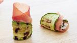 Gustosi rotolini di zucchine e bresaola su sfondo chiaro