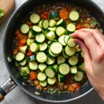 Pezzetti di zucchine verdi aggiunti alla carne nel tegame con un velo d'acqua.