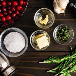 Tritate finemente il rosmarino e gli spicchi di aglio. Distribuite uniformemente il trito sulla superficie del cappone