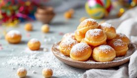 Castagnole dorate ricoperte di zucchero a velo su piatto.