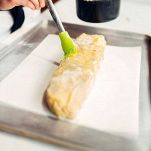 Spennellate bene tutto il rotolo chiuso con il burro chiarificato fuso e infornatelo in una teglia foderata di carta da forno con forno statico a 180°