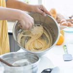 In un'altra ciotola, unite il tuorlo pastorizzato, i semi della bacca di vaniglia, il restante zucchero e un pizzico di sale