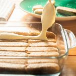 In una pirofila da 20x20cm, iniziate con un sottile strato di crema al mascarpone, quindi disponete uno strato di savoiardi inzuppati