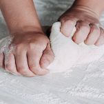 Mani femminili preparano l'impasto per la pizza