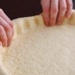 Impasto della pizza nello stampo sistemano da mani femminili