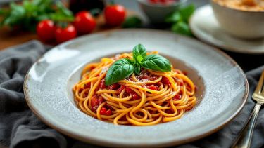 Spaghetti con sugo di pomodorini e formaggi fusi dall’aspetto cremoso e invitante.