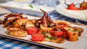 Calamari grigliati con pomodorini e olive su piatto bianco