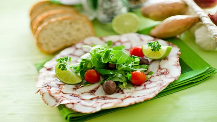 Vassoio con gustoso carpaccio di polpo con pomodorini e olive