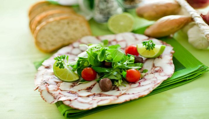 Vassoio con gustoso carpaccio di polpo con pomodorini e olive