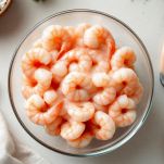 Mettete i gamberetti sgusciati in una ciotola e aggiungete la salsa cocktail