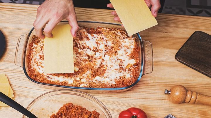 mani che preparano la lasagna