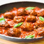 Meatballs in tomato sauce with basil in frying pan