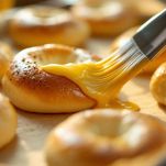 Bagel spennellati con uovo sbattuto e pronti per essere infornati