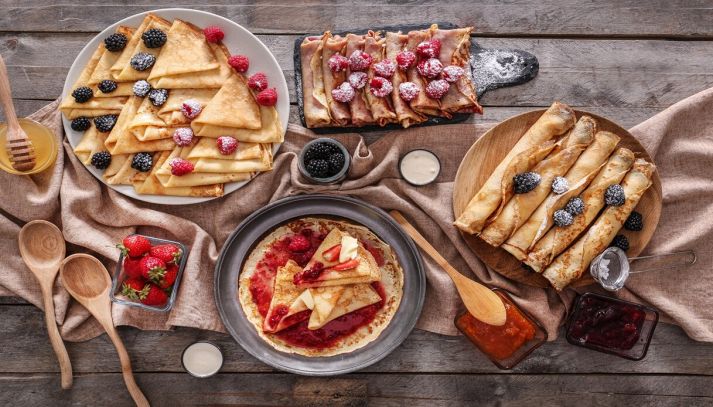 composizione di frittelle con frutti di bosco e marmellata sul tavolo