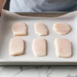 Teglia con filetti di merluzzo crudi su carta forno.