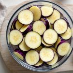 Fette di melanzane in ammollo in acqua salata.