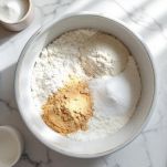 Ciotola con farina, lievito e zucchero mescolati.