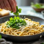 Tagliatelle con piselli guarnite con prezzemolo e pecorino.