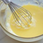 Uova e zucchero montati in ciotola con frusta.