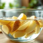 Patate a spicchi immerse in ciotola con acqua fredda.