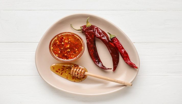 Piatto con miele caldo e peperoncino su fondo di legno chiaro