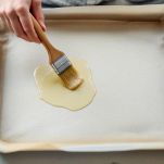 Teglia foderata di carta da forno su piano di lavoro.