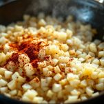 Cipolla, aglio e spezie che soffriggono in padella con olio.