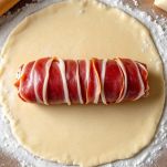 Filetto avvolto in pasta sfoglia su piano di lavoro.