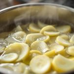 Finocchi bolliti scolati e affettati su tagliere.