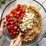 Pomodori e caciotta tagliati a cubetti uniti al farro in ciotola.