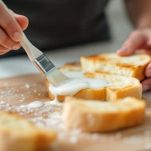 Pennello da cucina che spennella latte su fetta di pane integrale.