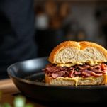 Panino farcito che cuoce sulla piastra con superficie dorata.