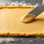 Impasto di ceci steso su piano liscio con coltello.