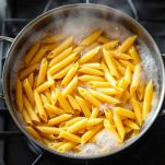 Pasta che cuoce in pentola con acqua bollente salata.