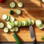 Zucchine affettate a rondelle sottili su tagliere.
